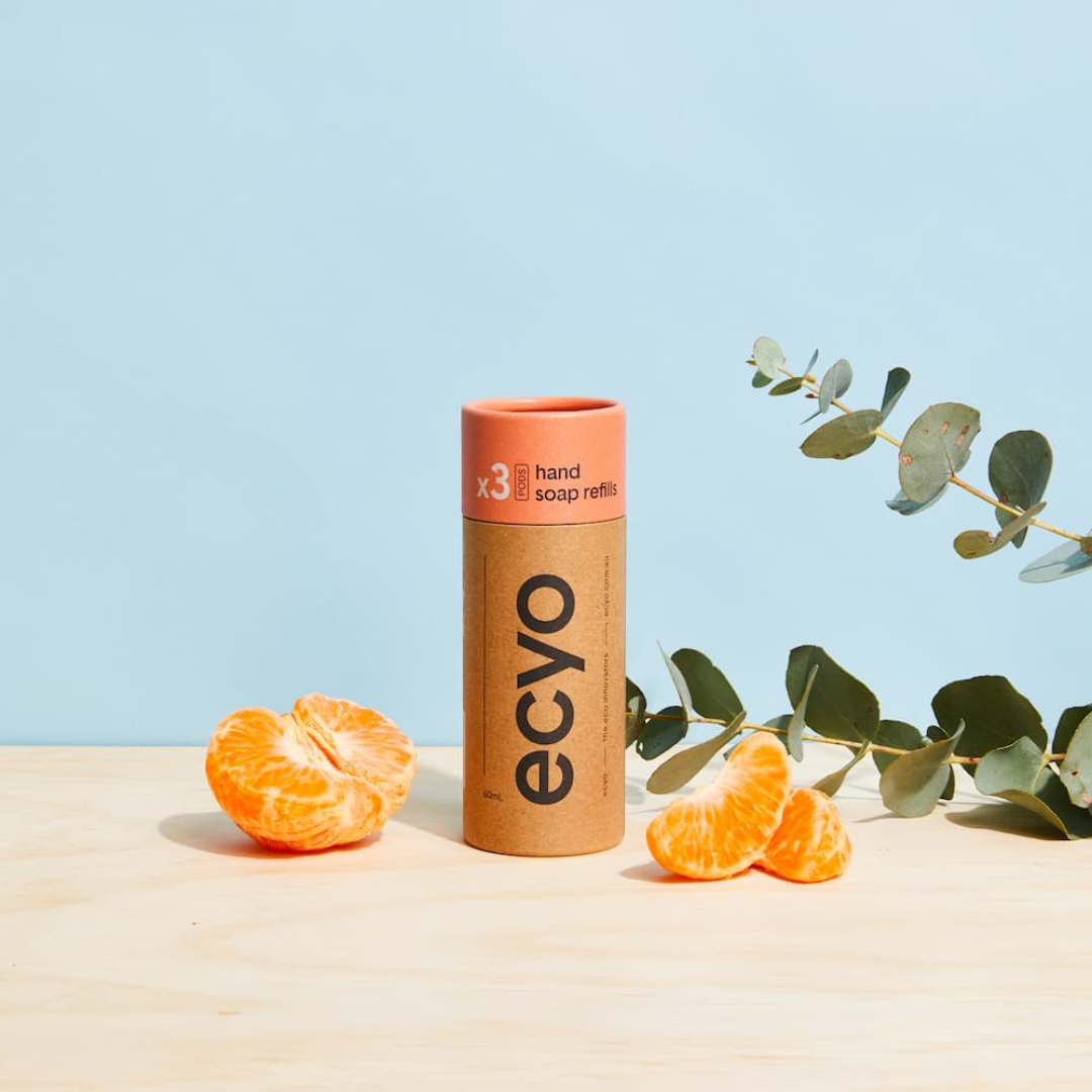 Eco-friendly hand soap refills with oranges and eucalyptus leaves on a light blue background