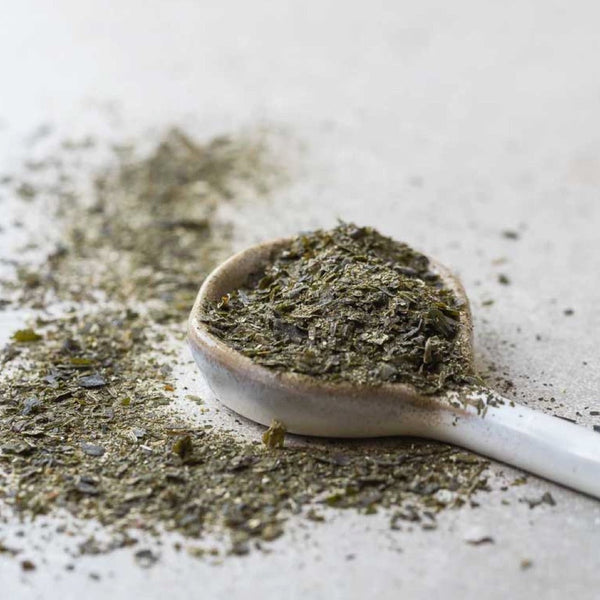 Spoonful of green powder on a light surface