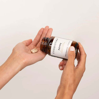 Person holding a bottle of Cymbiotika NMN supplements with a white background