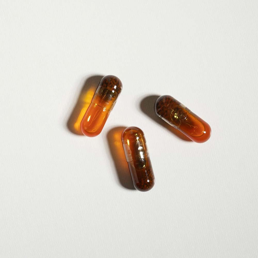 Three amber-colored capsules on a light gray background
