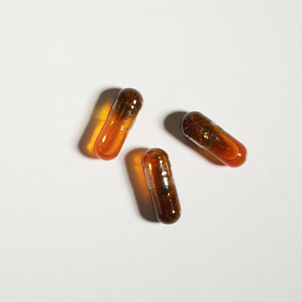 Three amber-colored capsules on a light gray background