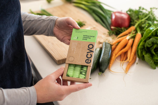 Person holding a box of Ecyo products on a table with vegetables