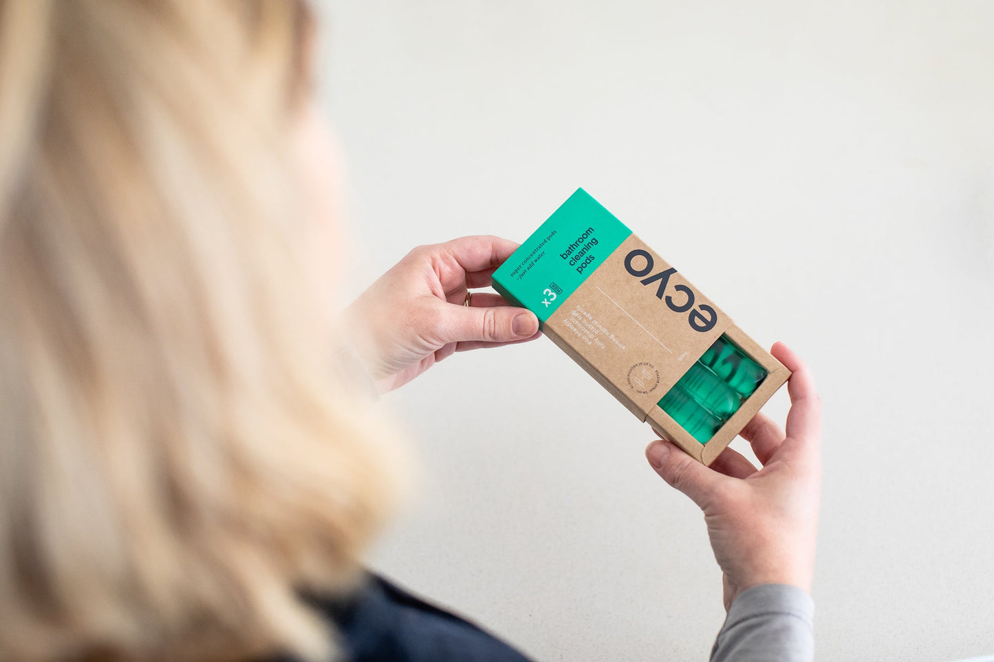 Person holding a cardboard box with 'ecyo' branding against a plain background