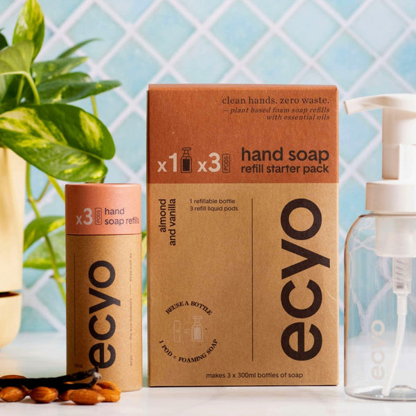 Ecyo eco-friendly hand soap refill kit with cardboard box and bottles on a light blue tiled background.