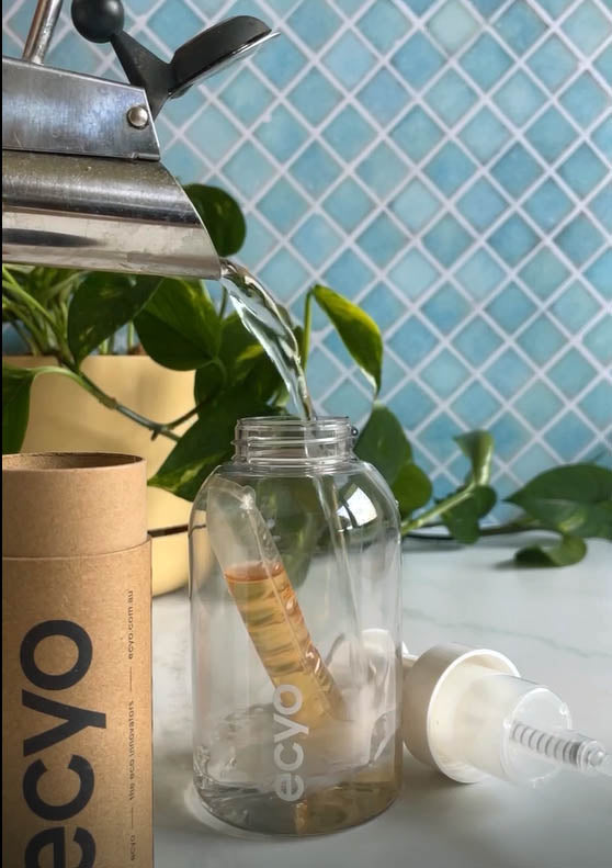 Clear bottle being filled with water from a faucet, with 'ecyo' branding visible.