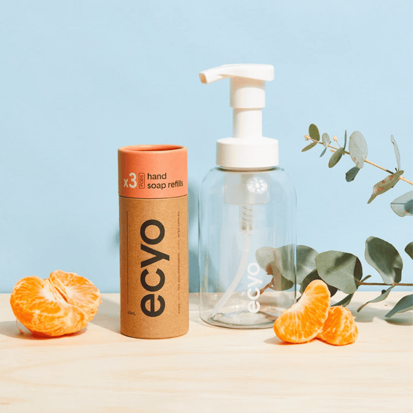 Ecyo eco-friendly hand soap bottle and refill container with oranges and eucalyptus on a light blue background