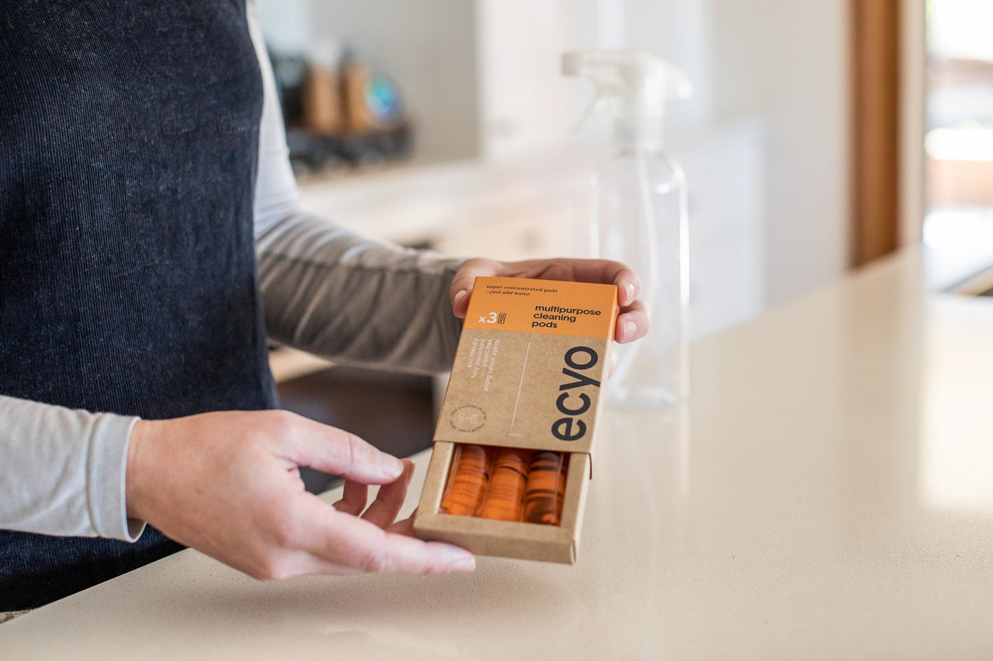 Person holding a box of Ecyo cleaning wipes in a kitchen setting