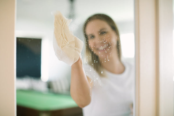 Woman cleaning a window with a cloth, indoors.