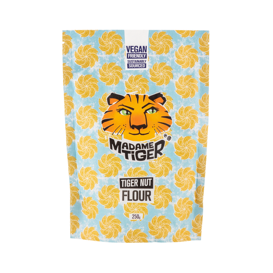 Packaging of Madame Tiger Tiger Nut Flour with tiger face logo on a blue background with yellow swirls.