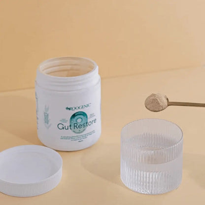 Roogenic Gut Restore supplement jar with a spoonful of powder on a beige background