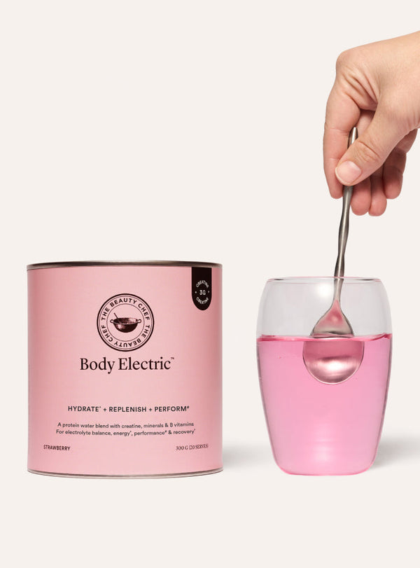 The beauty chef protein powder canister with a glass of pink liquid and a spoon, labeled 'Body Electric'.